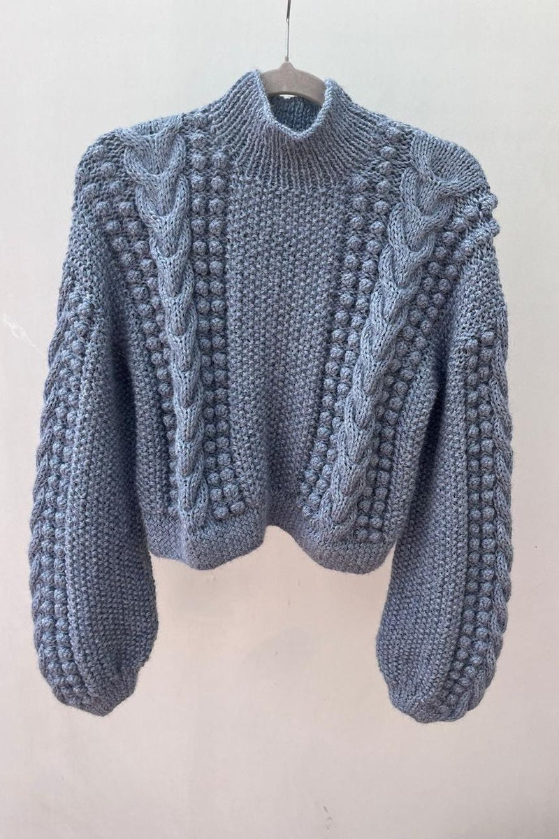 Blue knitted sweater on a hanger against a white background